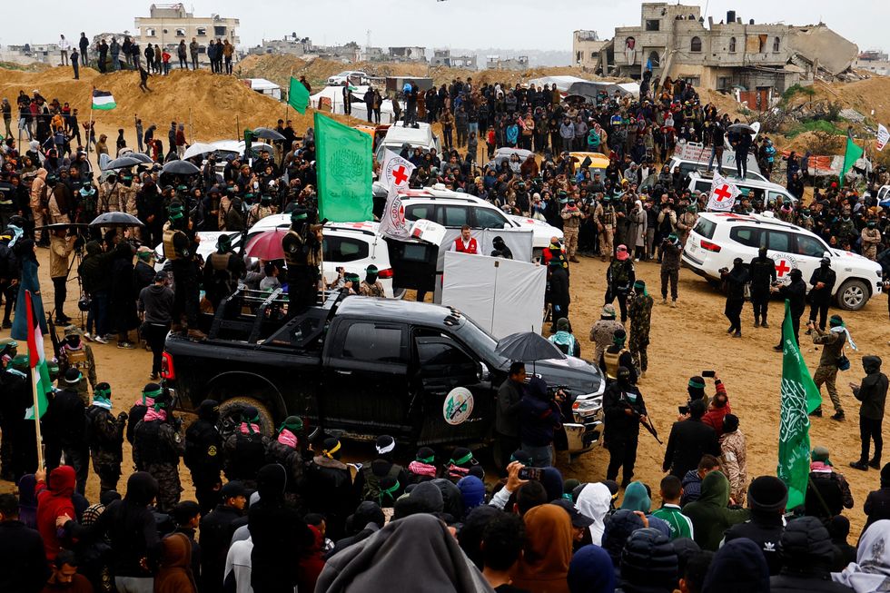 \u200bPalestinian militants and members of the Red Cross gather near vehicles on the day Hamas hands over deceased hostages