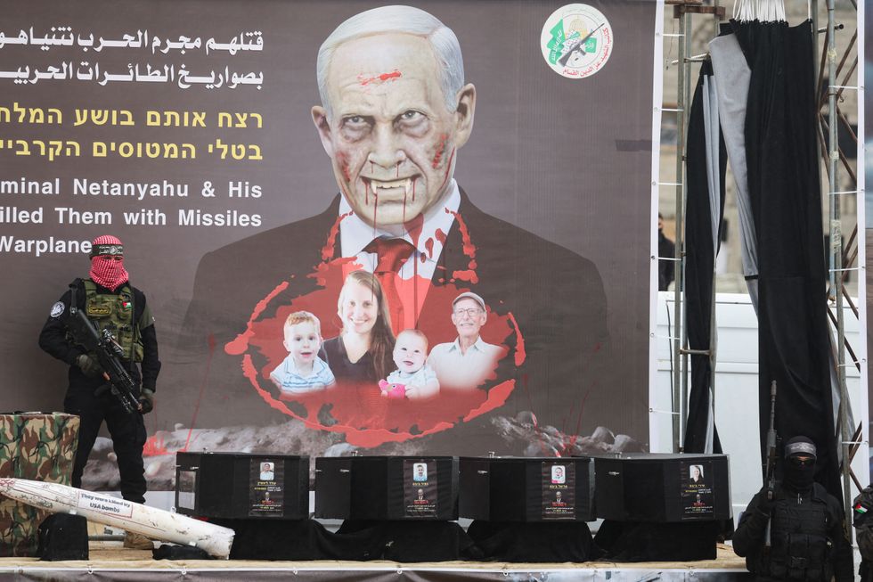 \u200bPalestinian militants stand near coffins during the handover of deceased hostages Oded Lifschitz, Shiri Bibas and her two children Kfir and Ariel Bibas