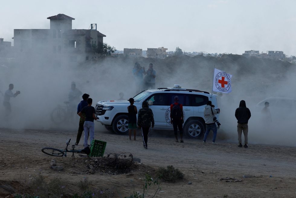 \u200bPalestinians gather around a Red Cross vehicle transporting hostages, held in Gaza since