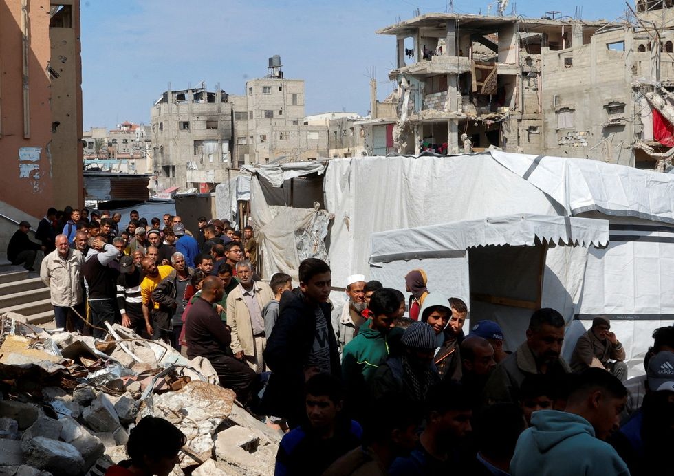 \u200bPalestinians gather to receive bread from a bakery, in Khan Younis