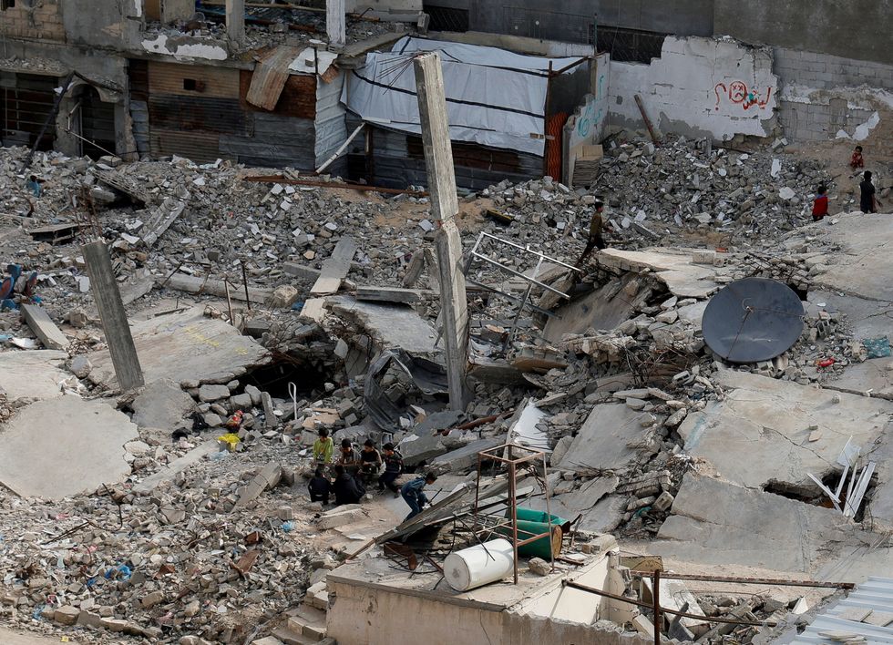 \u200bPalestinians sit amid rubble of houses, in Khan Younis in the southern Gaza Strip
