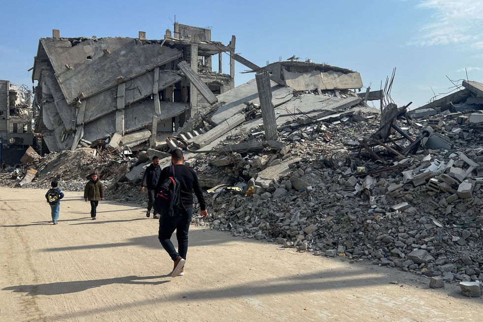 \u200bPalestinians walk past the rubble of destroyed houses, amid a ceasefire between Israel and Hamas,