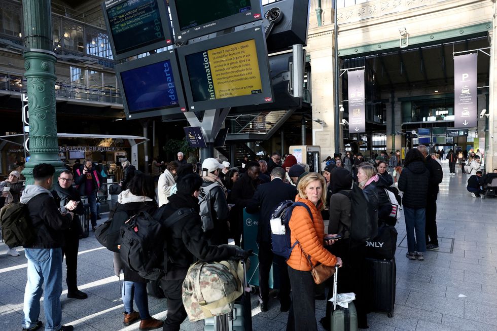 \u200bPassengers stand next to information screens at the departure hall