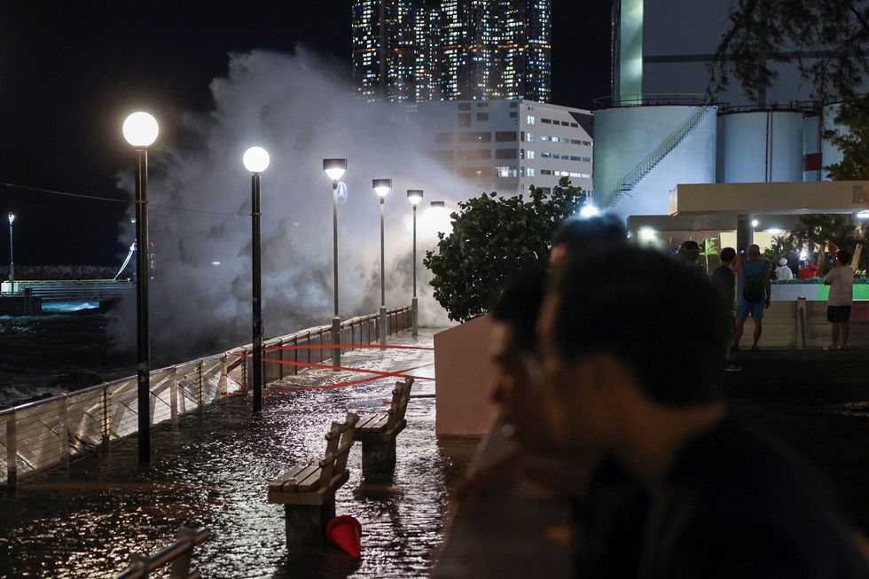 \u200bPedestrians look on as waves the size of lampposts batter the seafront