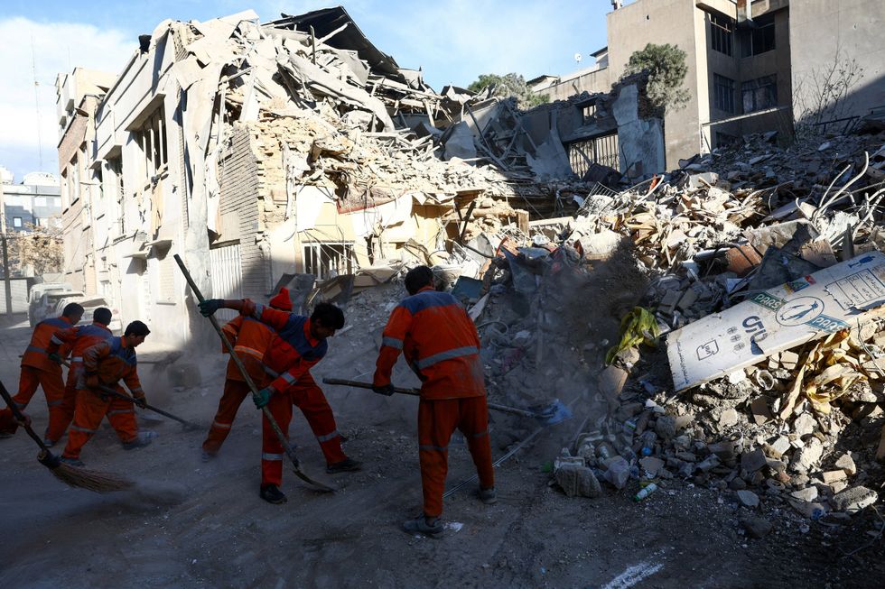 \u200bPeople clear rubble of a Synagogue, which was damaged in a strike, from a street,