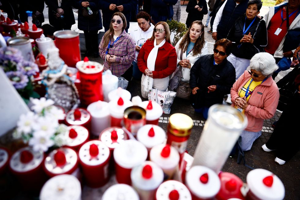 \u200bPeople pray next to the statue of the late Pope John Paul II outside Gemelli Hospital,
