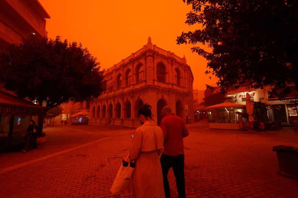 \u200bPeople walk amid a haze caused by sand dust from the Sahara, due to strong southern winds, in Heraklion