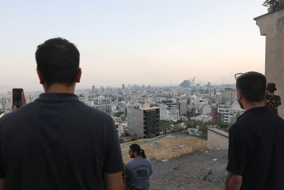 \u200bPeople watch as smoke rises following an Israeli attack on the IRIB building