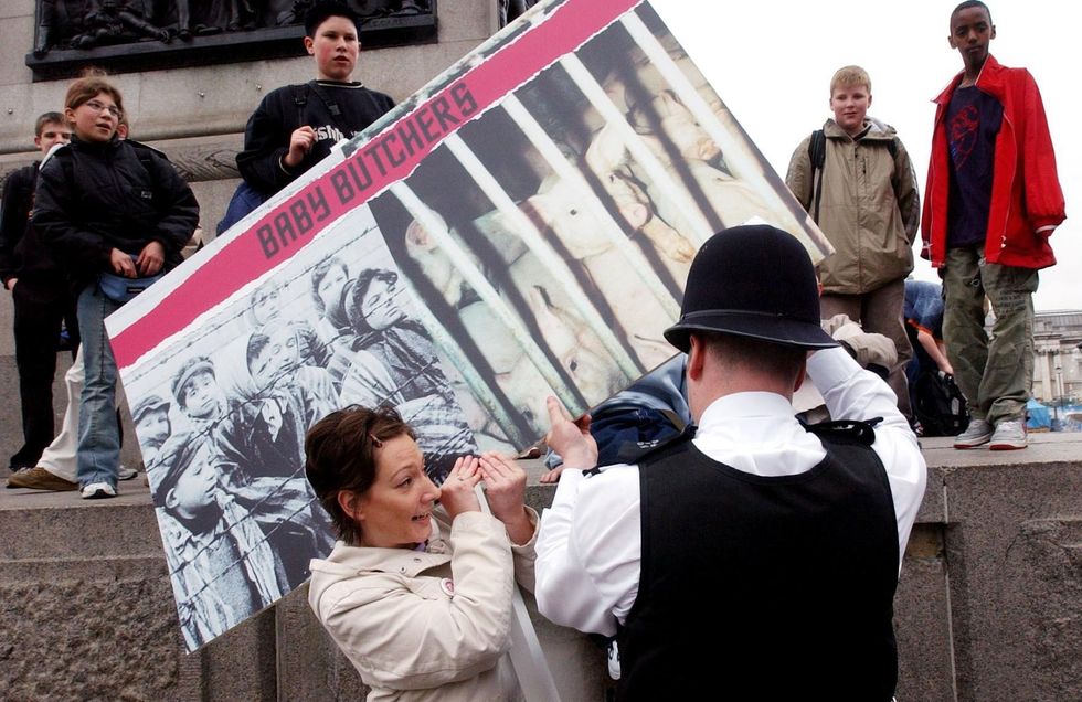 \u200bPeta protester holding placard showing Jews in concentration camp next to pigs in a cage