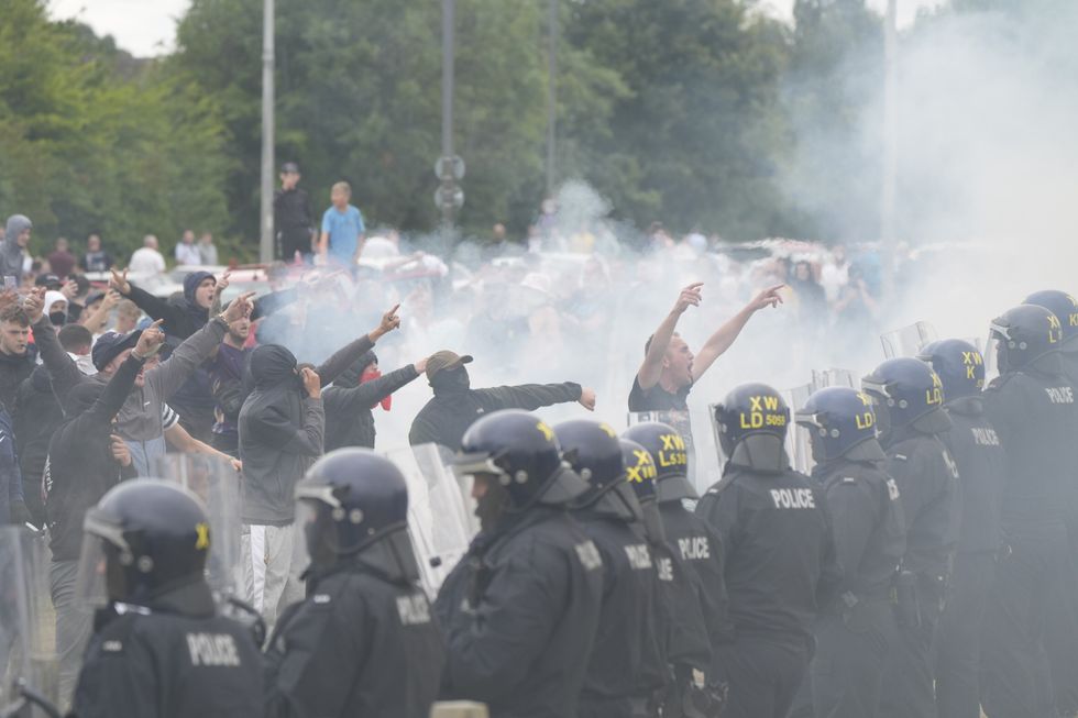 \u200bPolice officers face protesters during an anti-immigration demonstration outside the Holiday Inn Express in Rotherham