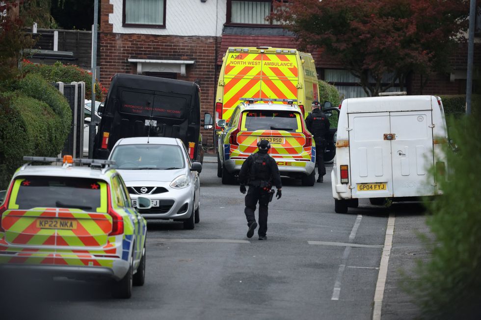 \u200bPolice officers work outside a house close to the scene,