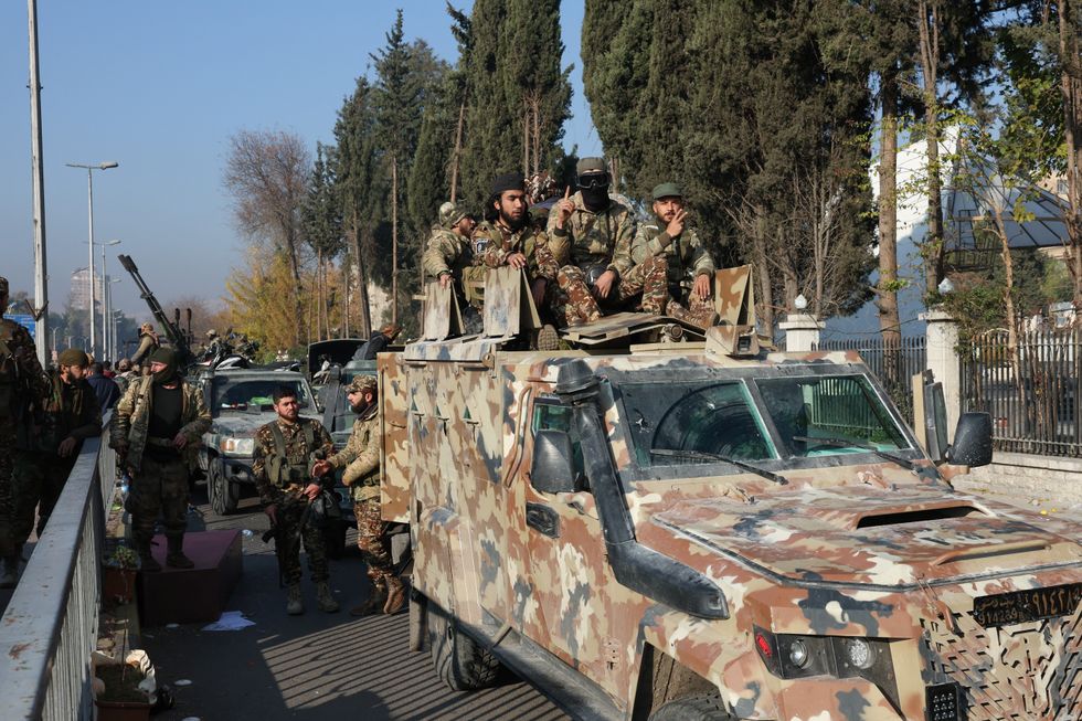 \u200bRebel fighters sit on a vehicle, after rebels seized the capital and ousted President Bashar al-Assad