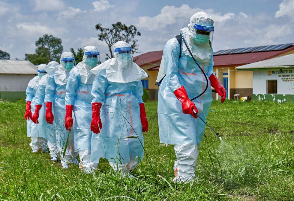 \u200bRed Cross workers walk in a formation as they disinfect Rwampara general hospital