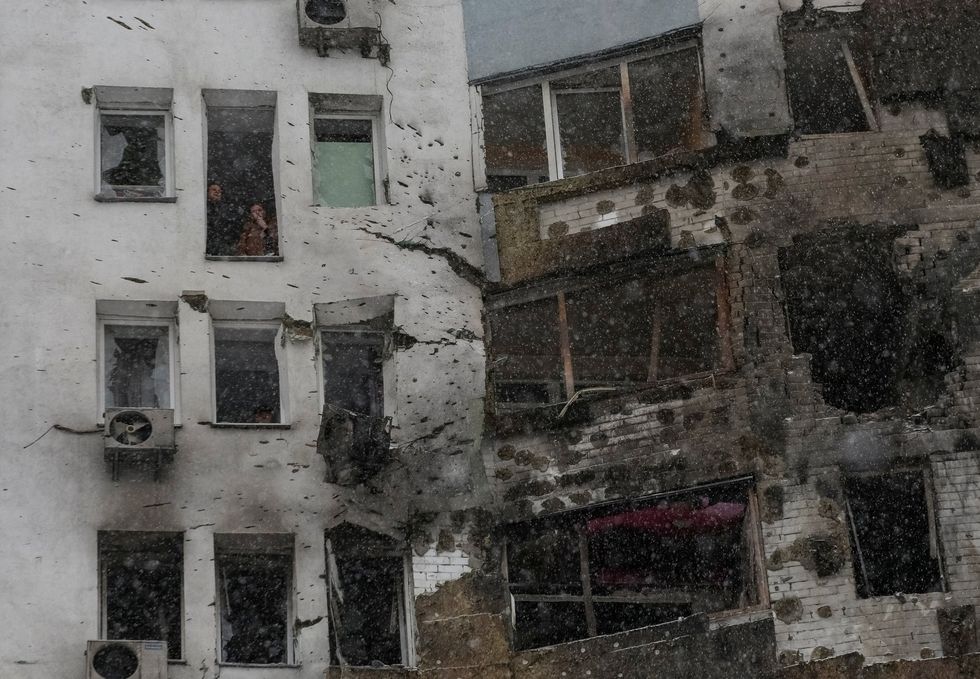 \u200bResidents smoke near a broken window of their apartment, damaged during Russian drone strike,