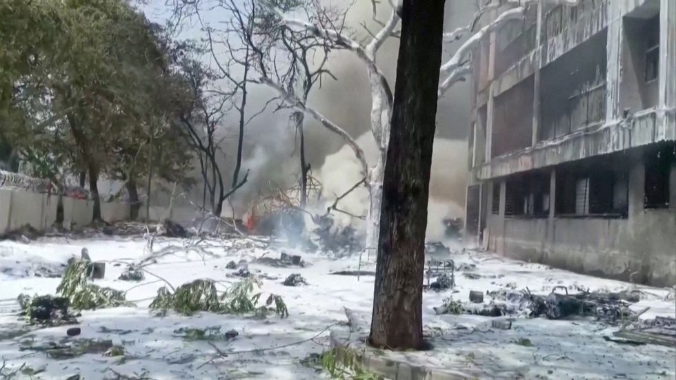 \u200bSmoke rises near a damaged building and trees after an Air India plane crashed in Ahmedabad