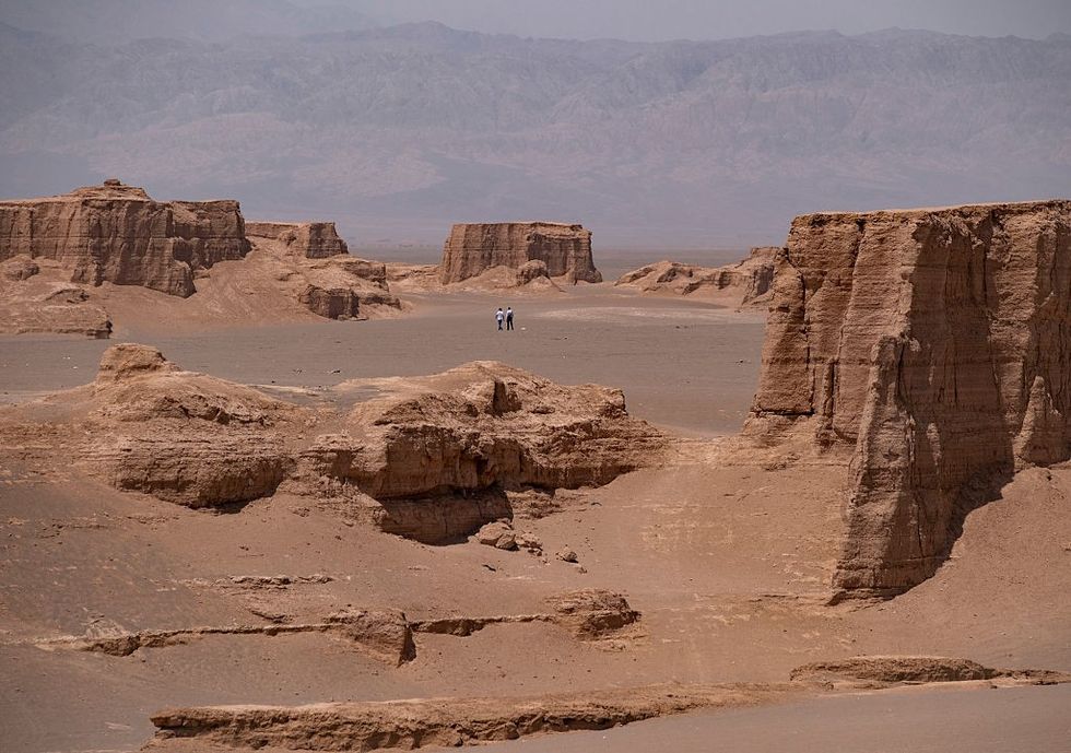 \u200bTwo Iranian tourists visit natural landforms created by wind erosion in arid desert environments in the Shahdad Kalut Desert near the city of Kerman