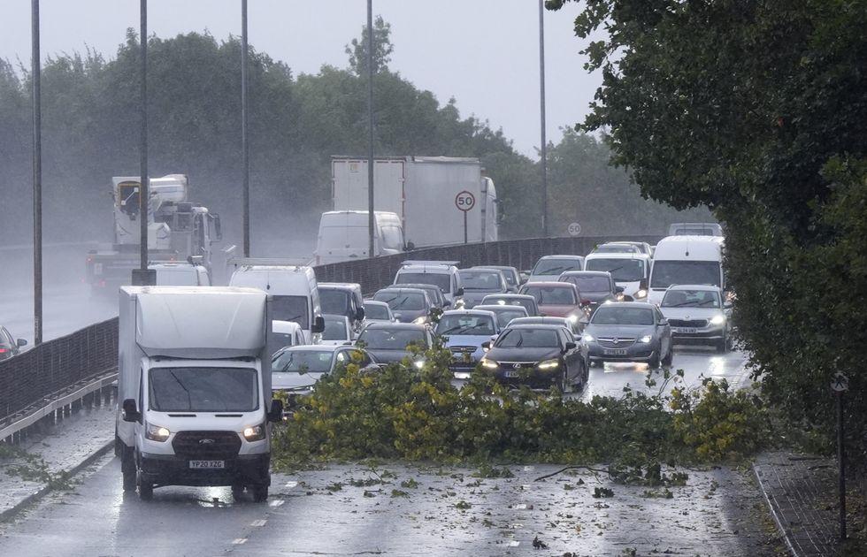 \u200bVehicles negotiate debris from a tree on the North Circular in London