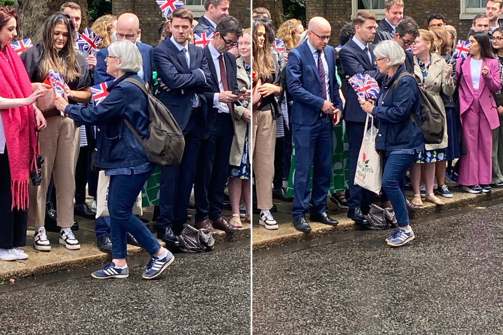 \u200bWoman hands out flags to supporters on Downing Street