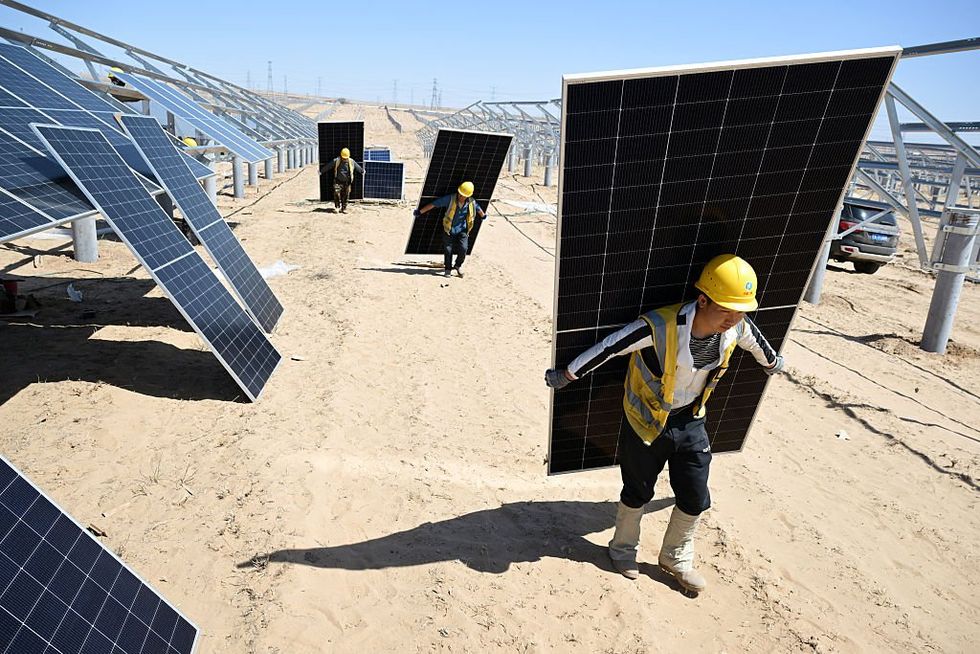\u200bWorkers carry solar panels to be installed in the desert at the Ningguoyun Lingwu 1 million kilowatt photovoltaic project in Lingwu