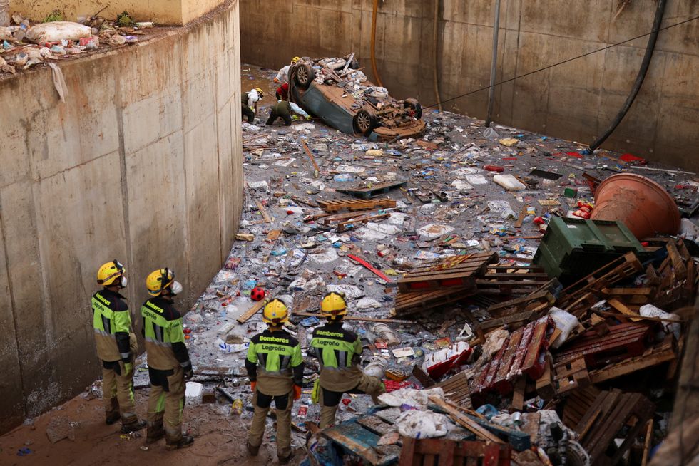 \u200bWorkers stare at mountain of rubbish and mud in Valencia