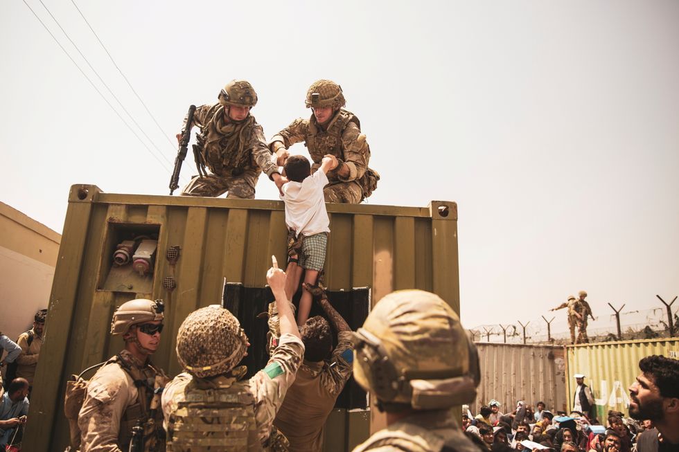 UK coalition forces, Turkish coalition forces, and U.S. Marines assist a child during an evacuation at Hamid Karzai International Airport, Kabul, Afghanistan.