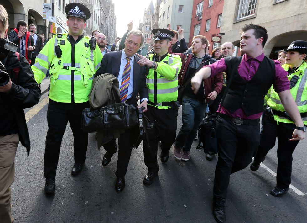 UKIP leader Nigel Farage is escorted by police officers as he leaves the Cannons Gait pub as protestors heckle him, following a press conference with journalists