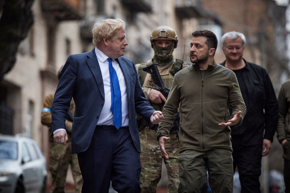 Ukraine's President Volodymyr Zelenskiy and British Prime Minister Boris Johnson speak as they walk along a street after a meeting, as Russia's attacks on Ukraine continue.