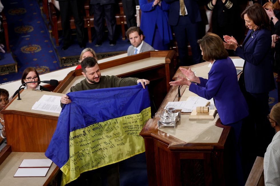 Ukraine's President Volodymyr Zelenskiy presents a Ukrainian flag given to him by defenders of Bakhmut to U.S. House Speaker Nancy Pelosi (D-CA) during a joint meeting of U.S. Congress in the House Chamber of the U.S. Capitol in Washington, U.S., December 21, 2022. REUTERS/Jonathan Ernst