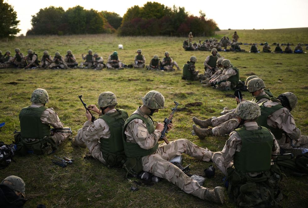 Ukrainian recruits lubricate their AK-47 assault rifles during a five-week combat training course with the UK armed forces