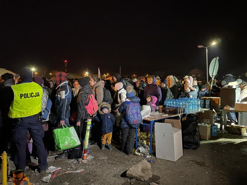 Ukrainian refugees stand in line awaiting transport in Medyka