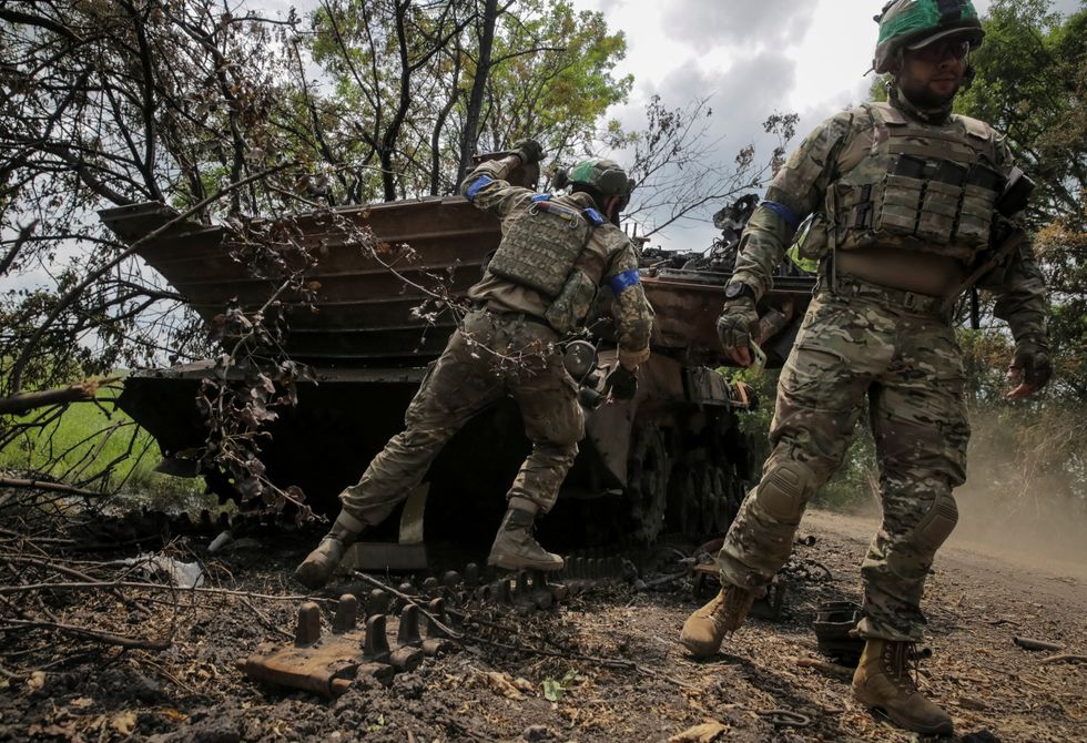 Ukrainian service members check a destroyed Russian a BMP-2 infantry fighting vehicle
