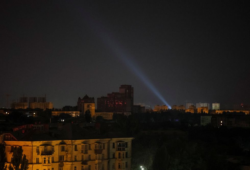 Ukrainian service personnel use a searchlight as they search for drones in the sky over the city during a Russian drone and missile strike