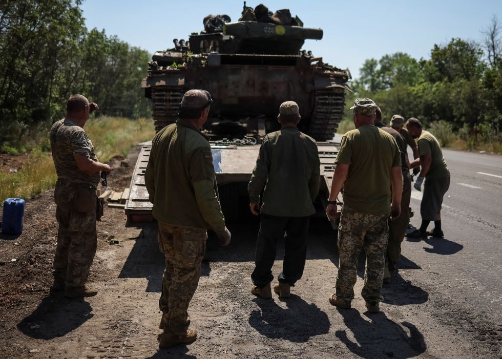 Ukrainian servicemen stand near a military truck with a tank on the road not far from front line, amid Russia's attack on Ukraine, in the Donbas region, Ukraine July 17, 2022. REUTERS/Gleb Garanich