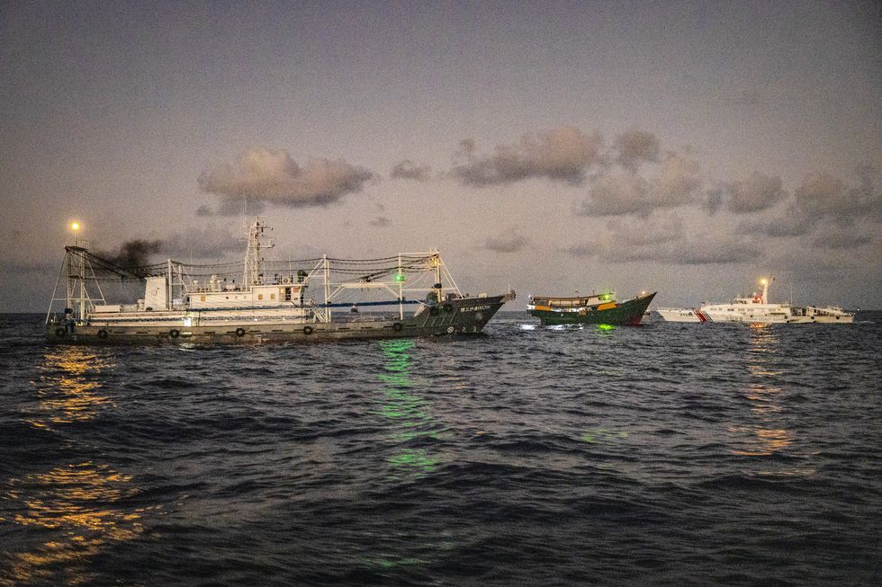 Unaizah May 4, a Philippine Navy chartered vessel, conducting a routine resupply mission to troops stationed at Second Thomas Shoal, is flanked by a Chinese Coast Guard