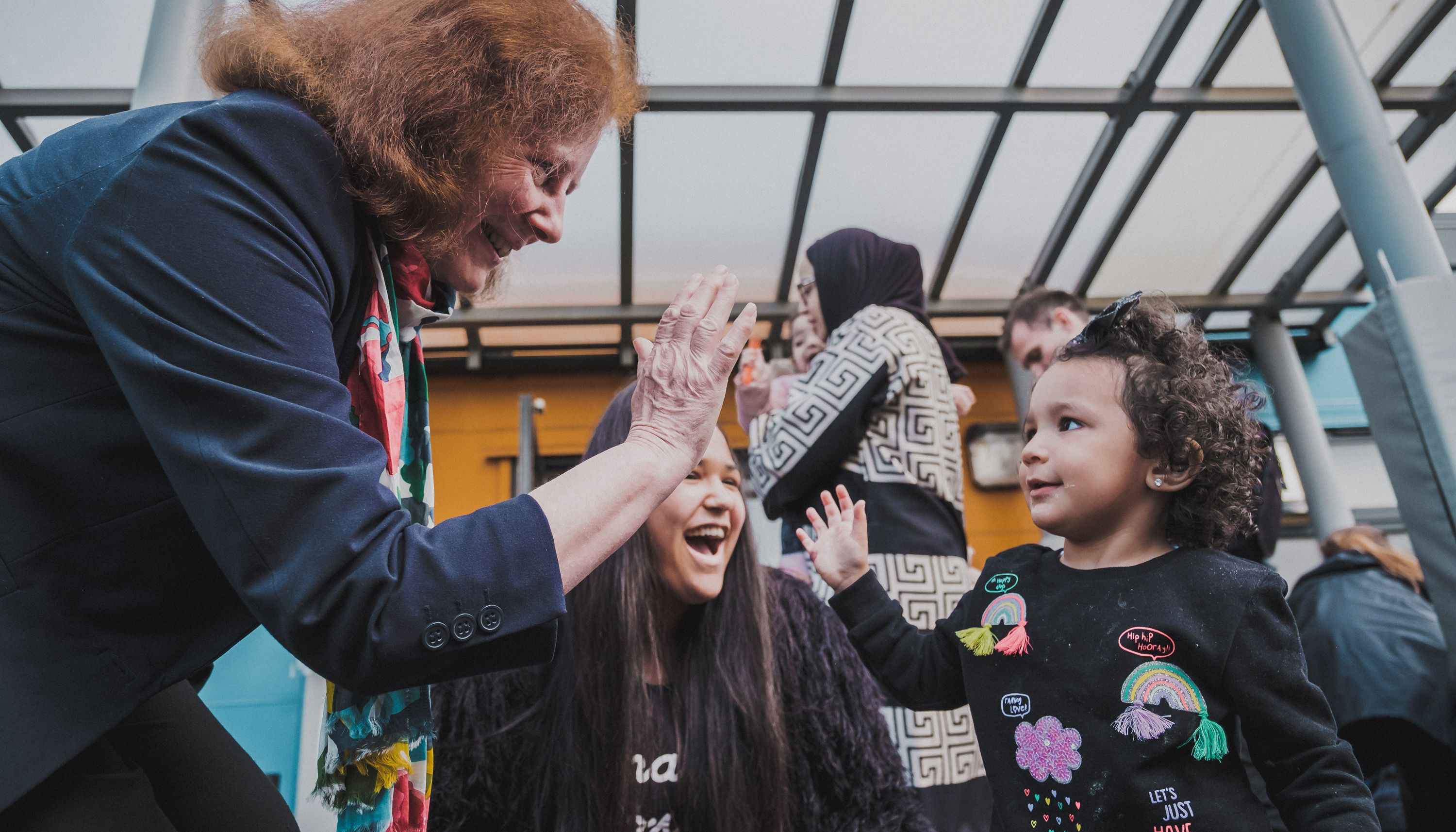 Undated handout photo issued by Welsh Government of Deputy minister for social services Julie Morgan high-fives a child in celebration of the new law banning the physical punishment of children.