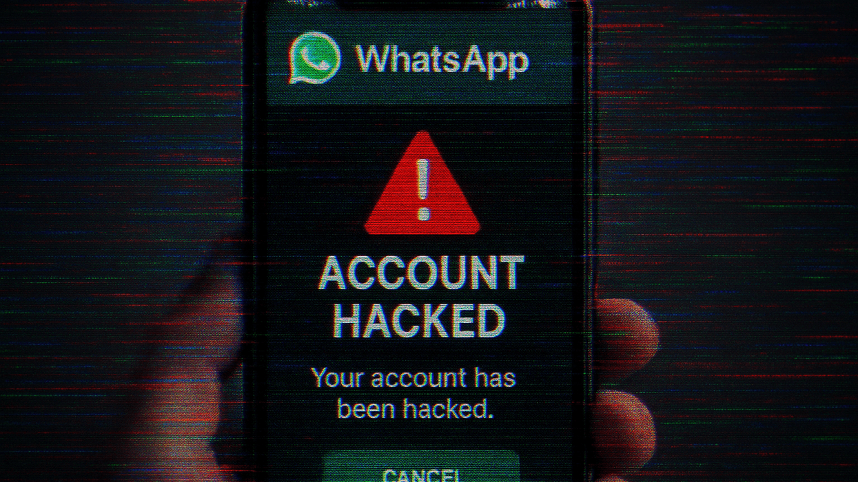 User holding phone with a notification that their WhatsApp account has been hacked