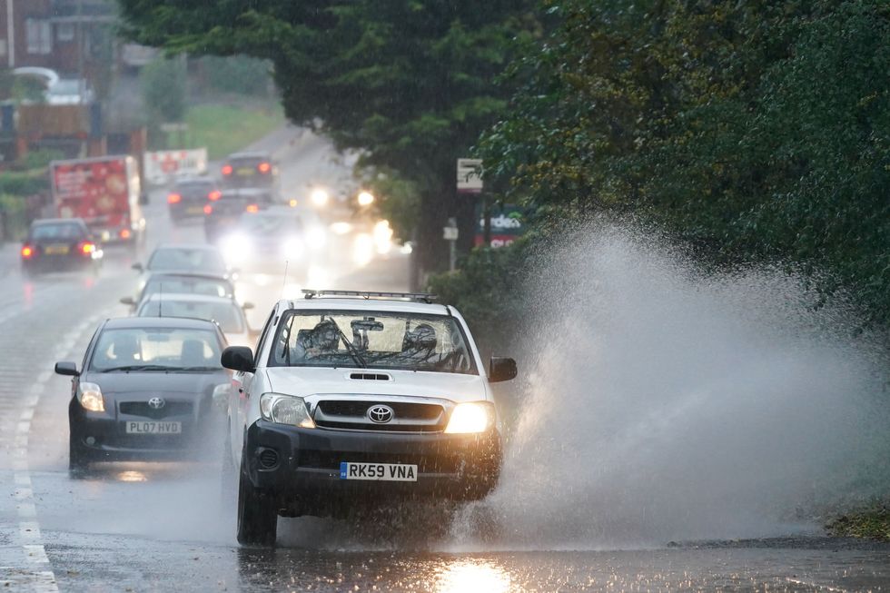 Vehicles travel through standing water during heavy rain in Bromsgrove