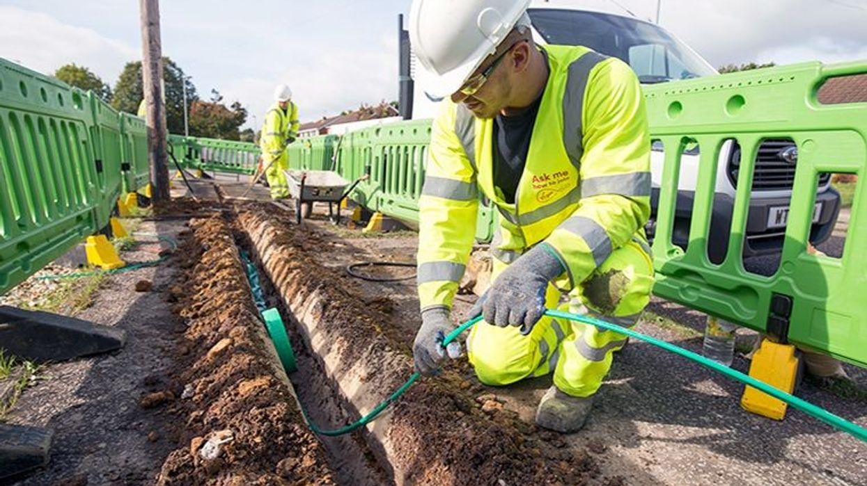 virgin media engineer in uniform pulling out a fibre-optic cable from the ground