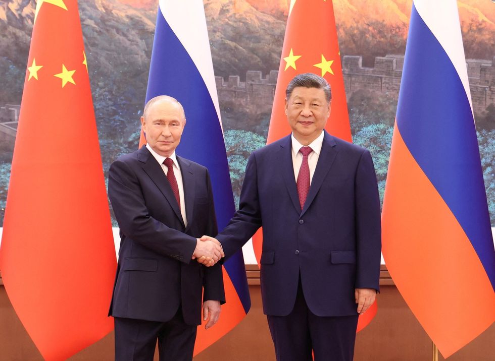 Vladimir Putin (right) and Xi Jinping (left) shaking hands as they pose for cameras