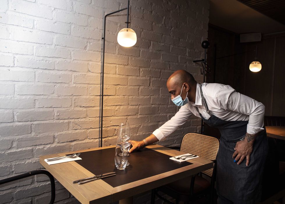Waiter Niven Bodi Reddy sets a table inside the Ely wine Bar, on Ely place in Dublin, where they will reopen for indoor dining on Thursday July 29. Picture date: Friday July 23, 2021.