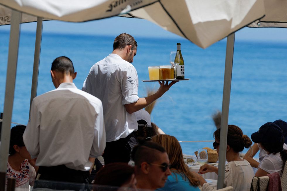 Waiters server drinks to customers at the terrace of restaurant on a hot summer day in Malaga, Spain, July 9, 2022. REUTERS/Jon Nazca