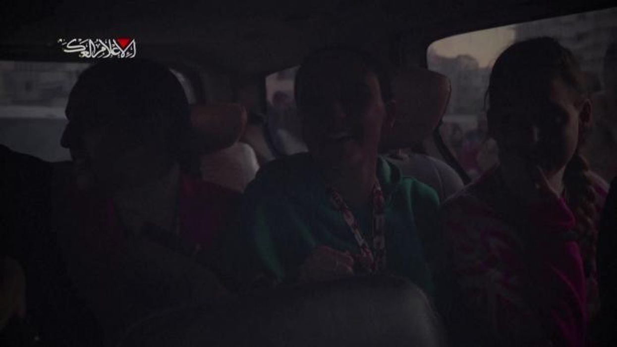 Watch: Hundreds of armed baclava-clad Hamas fighters jeer and torment hostage during handover to Red Cross