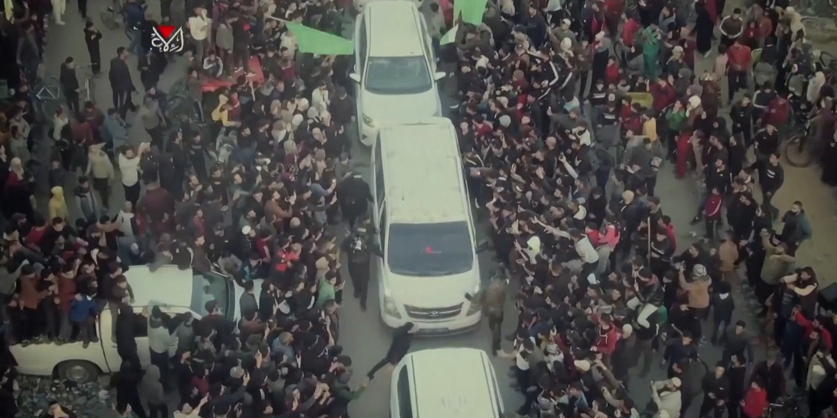 NextImg:Watch: Hundreds of armed baclava-clad Hamas fighters jeer and torment hostage during handover to Red Cross