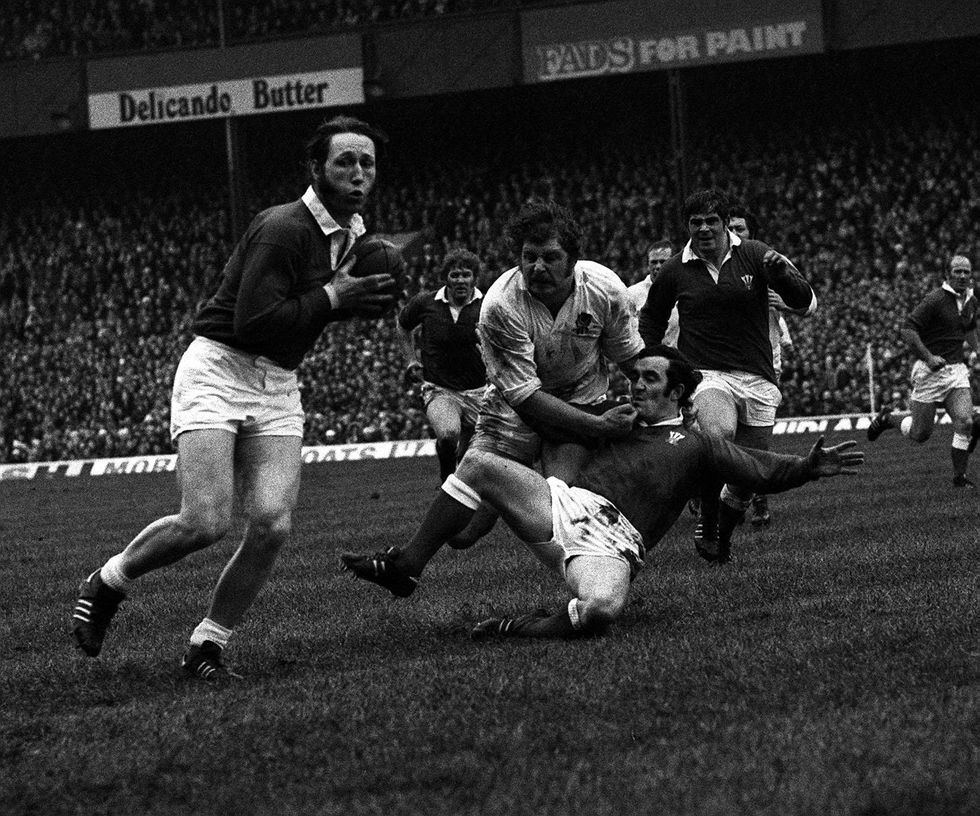 Welsh captain Phil Bennett (on ground) holds up England as JPR Williams gets the ball away for Wales
