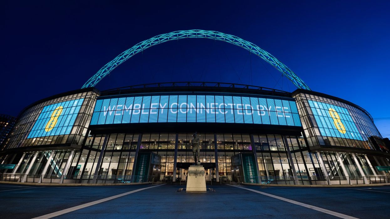 wembley stadium at night with the EE branding and logo visible on all screens