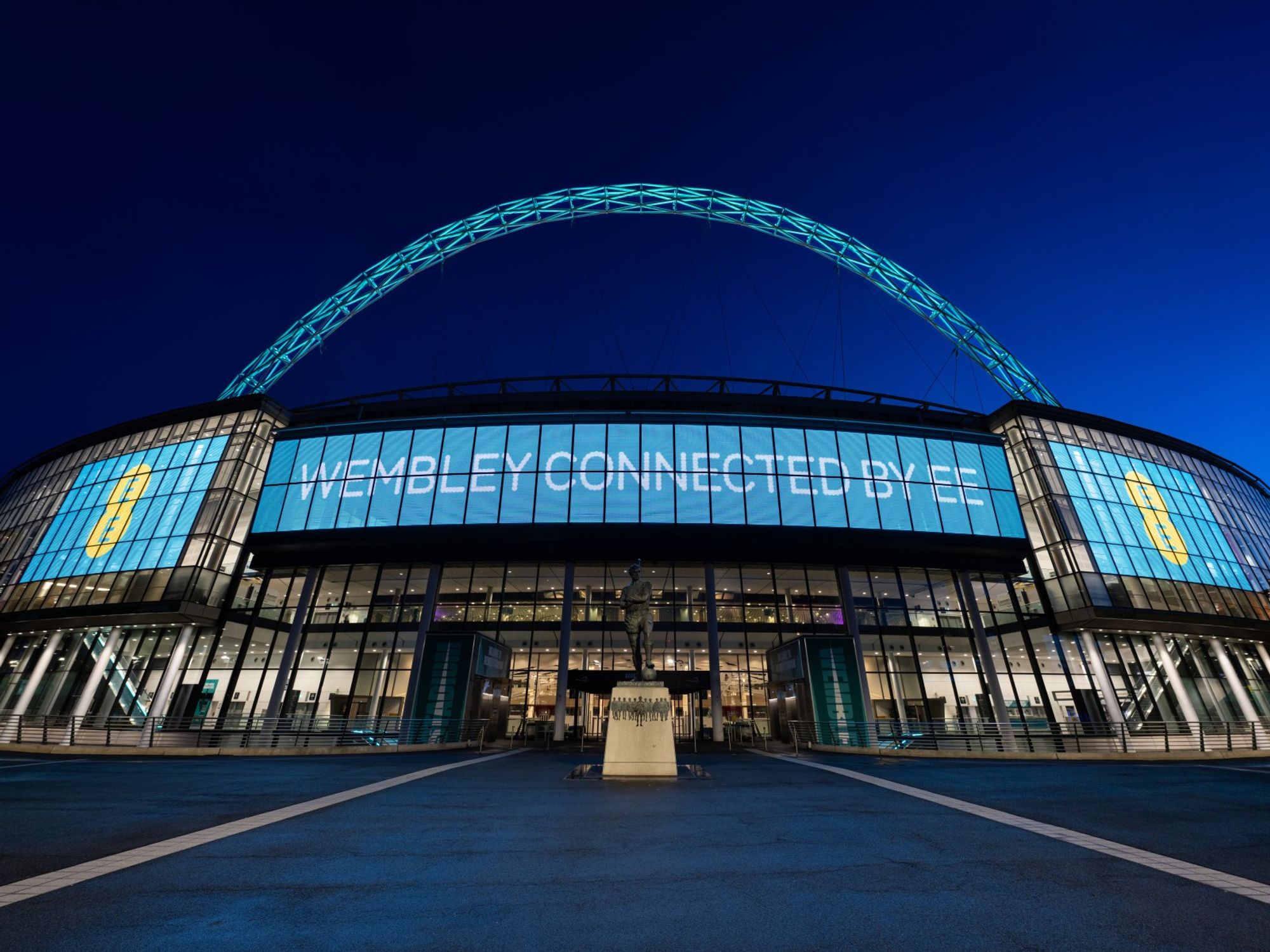 wembley stadium at night with the EE branding and logo visible on all screens