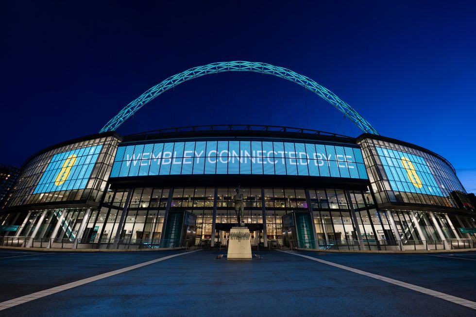 wembley stadium at night with the EE branding and logo visible on all screens 