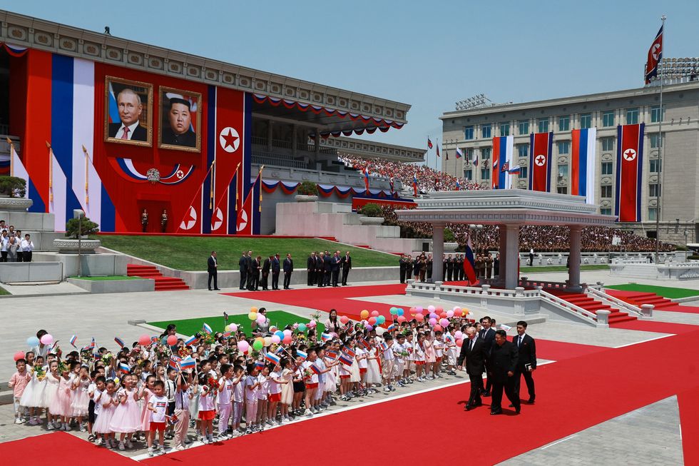 Wide shot of Putin and Kim with portraits in the background