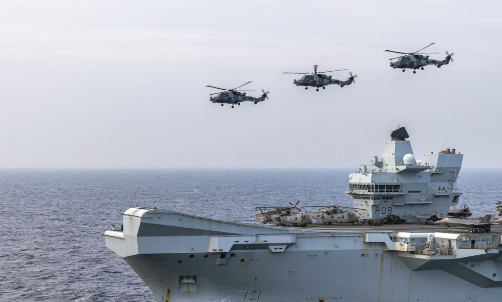 Wildcat Helicopters from 815 Naval Air Squadron fly past the HMS Prince of Wales