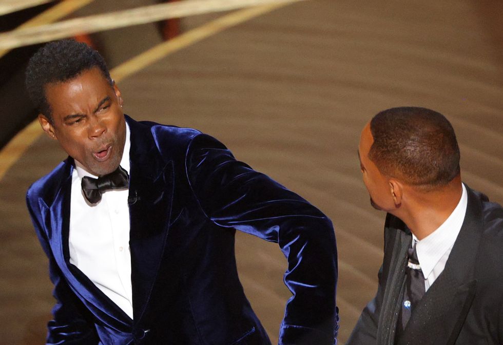 Will Smith (R) hits Chris Rock as Rock spoke on stage during the 94th Academy Awards in Hollywood, Los Angeles, California, U.S., March 27, 2022. REUTERS/Brian Snyder